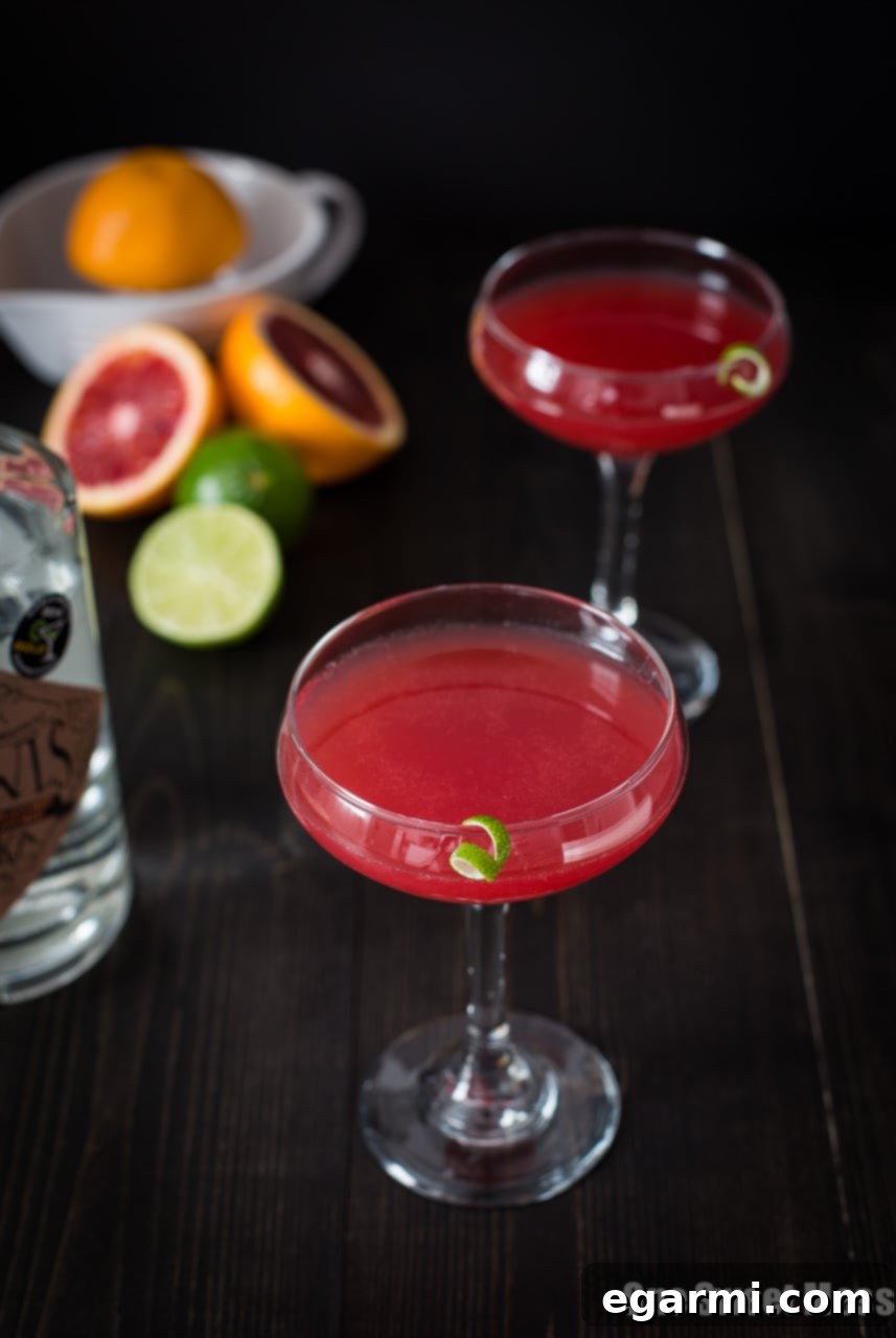 Ingredients for a Blood Orange Cosmo laid out: blood oranges, a lime, blood orange vodka, and triple sec bottles.