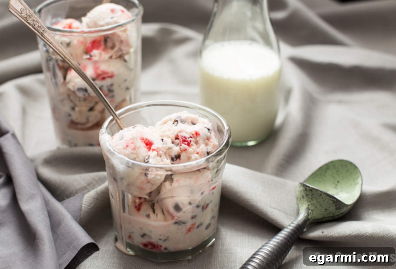 Three scoops of Cherry Chocolate Chip Ice Cream in a glass bowl, garnished with a fresh cherry