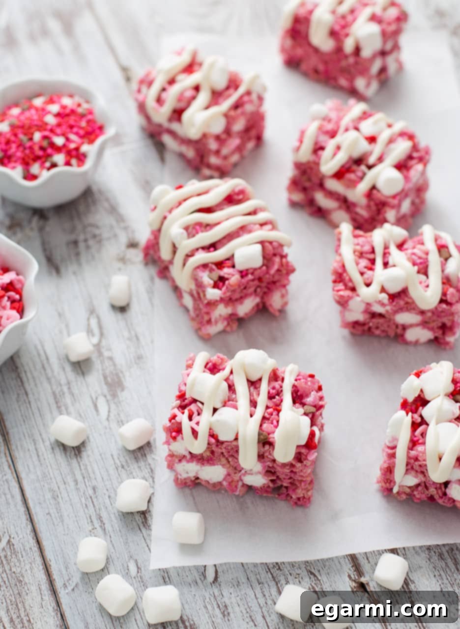 Red Velvet Krispie Treats 2 Gooey Red Velvet Rice Krispie Treats drizzled with white cream cheese glaze on a light background, ready for Valentine's Day.