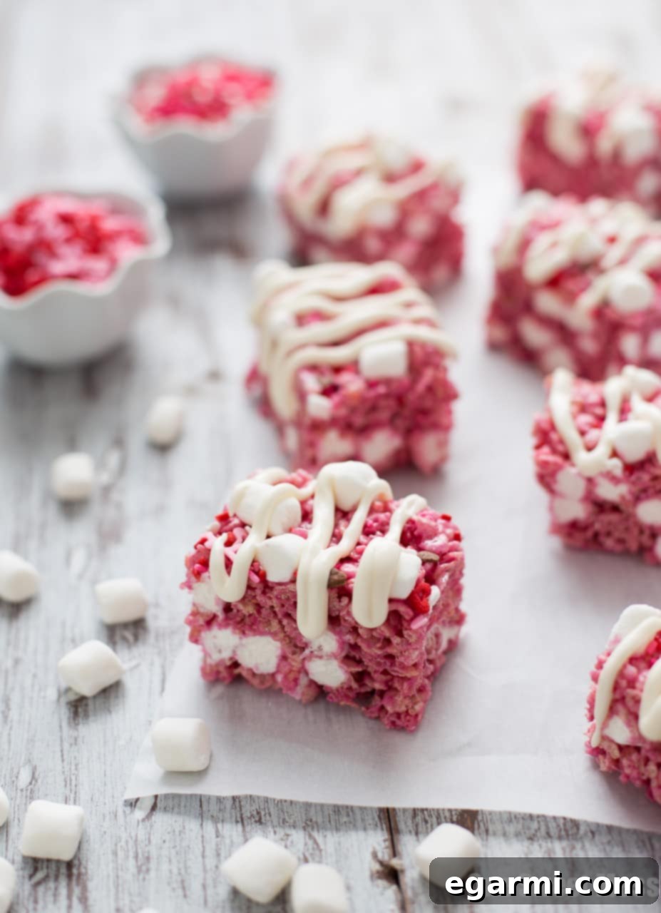 Red Velvet Krispie Treats 3 Stack of Red Velvet Rice Krispie Treats with a generous cream cheese glaze, topped with colorful sprinkles, perfect for a festive occasion.