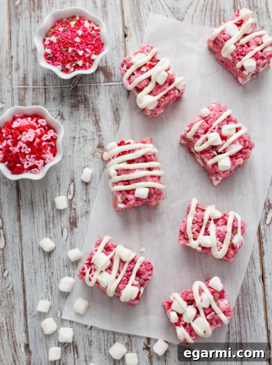Red Velvet Krispie Treats 5 Two Red Velvet Rice Krispie Treats, one fully glazed and sprinkled, the other partially glazed, on a white serving plate.