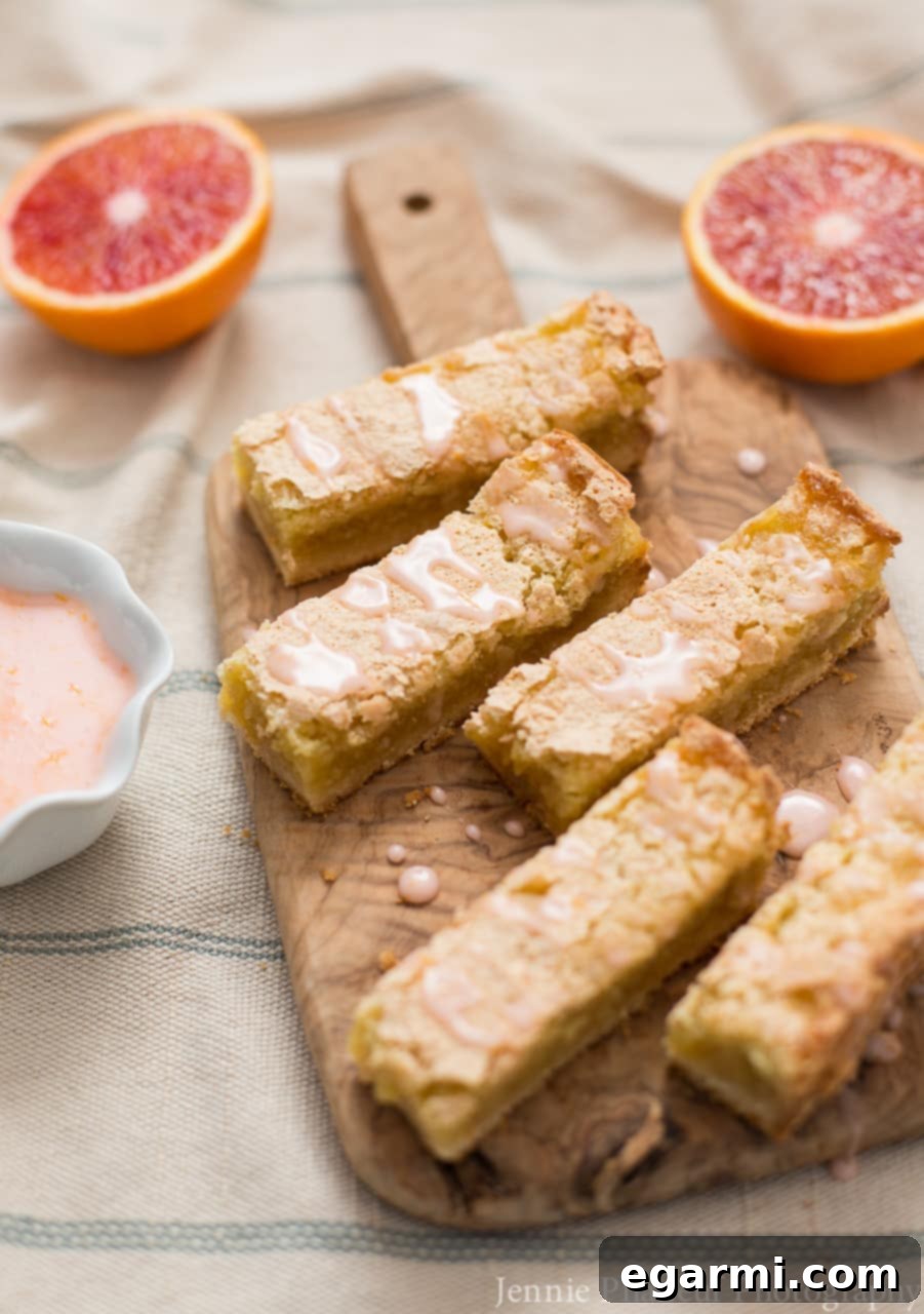 Blood Orange Bliss Bars, Vanilla Kissed 5 Freshly glazed Blood Orange Bars on a cooling rack, showcasing the rich pink glaze drizzled over the citrus bars