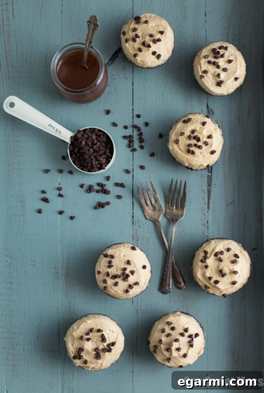 Three decadent Chocolate Stout Cupcakes with Whiskey Caramel Buttercream on a rustic surface