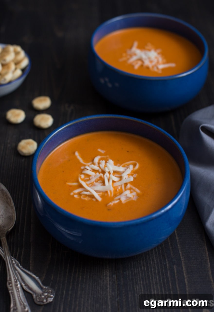 Close-up of creamy Roasted Red Pepper Smoked Gouda Soup with a swirl of cream.