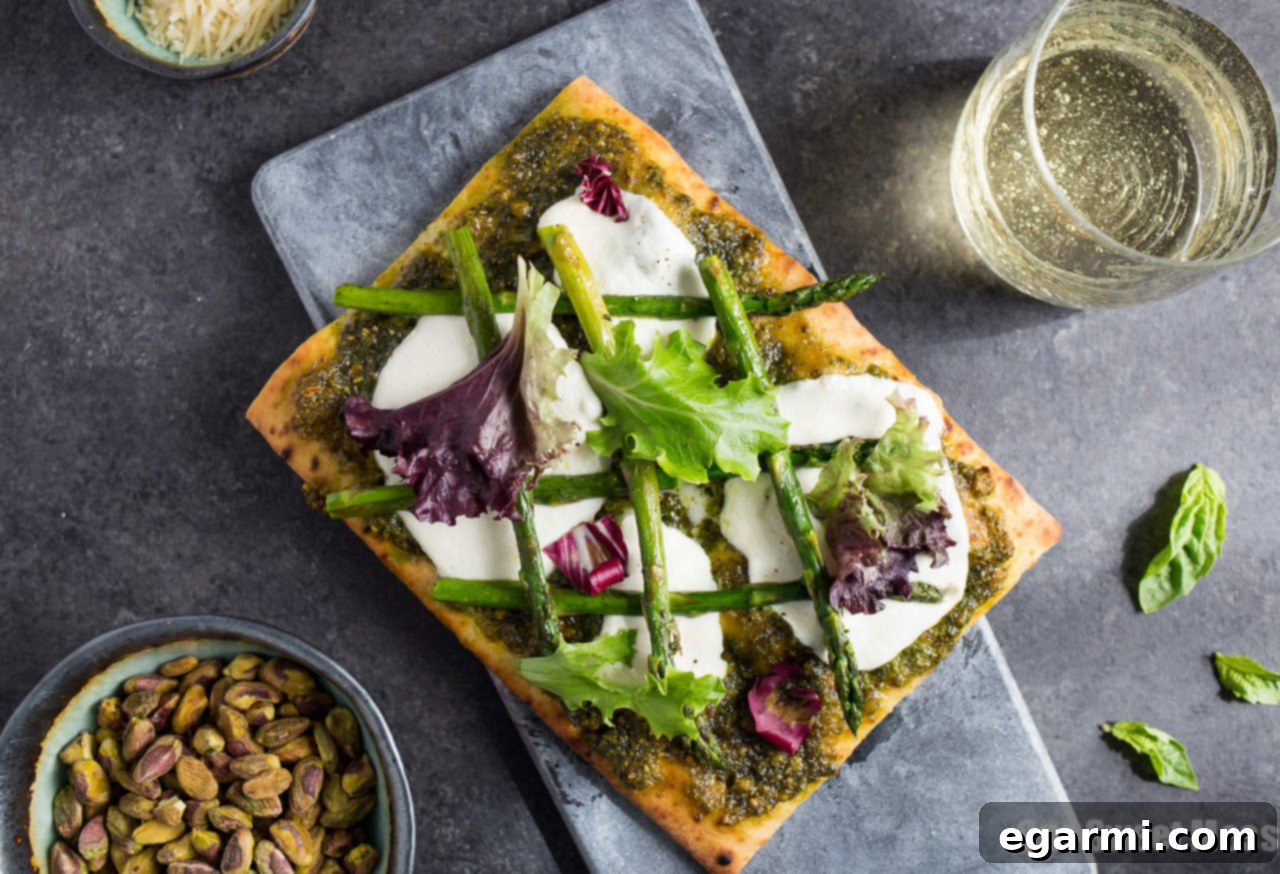 Artisan Pistachio Pesto Asparagus Flatbread Pizza 4 Individual Pistachio Pesto & Asparagus Flatbread Pizza cooking on a baking sheet.