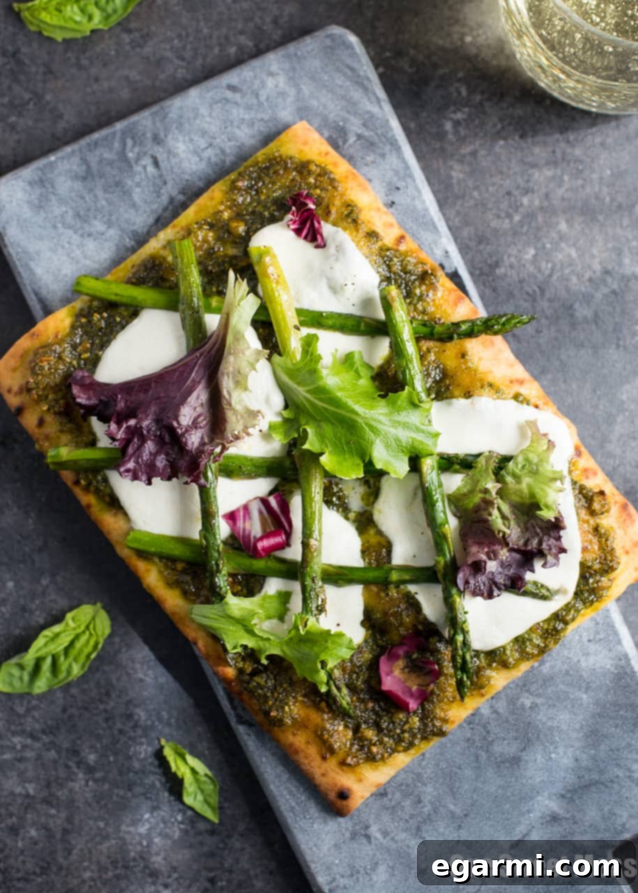 Artisan Pistachio Pesto Asparagus Flatbread Pizza 5 A close-up of a finished Pistachio Pesto & Asparagus Flatbread Pizza, garnished with arugula.