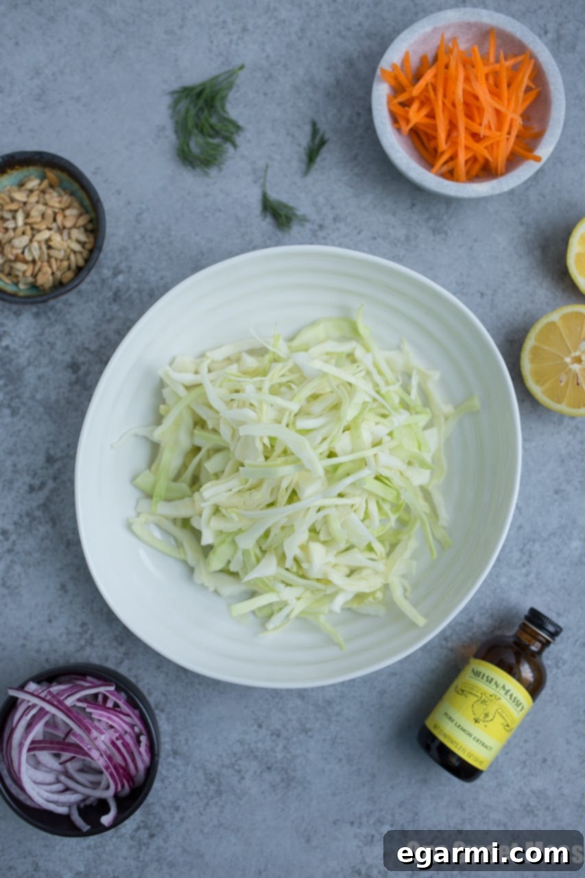 Creamy Lemon Dill Coleslaw dressing being poured over shredded vegetables