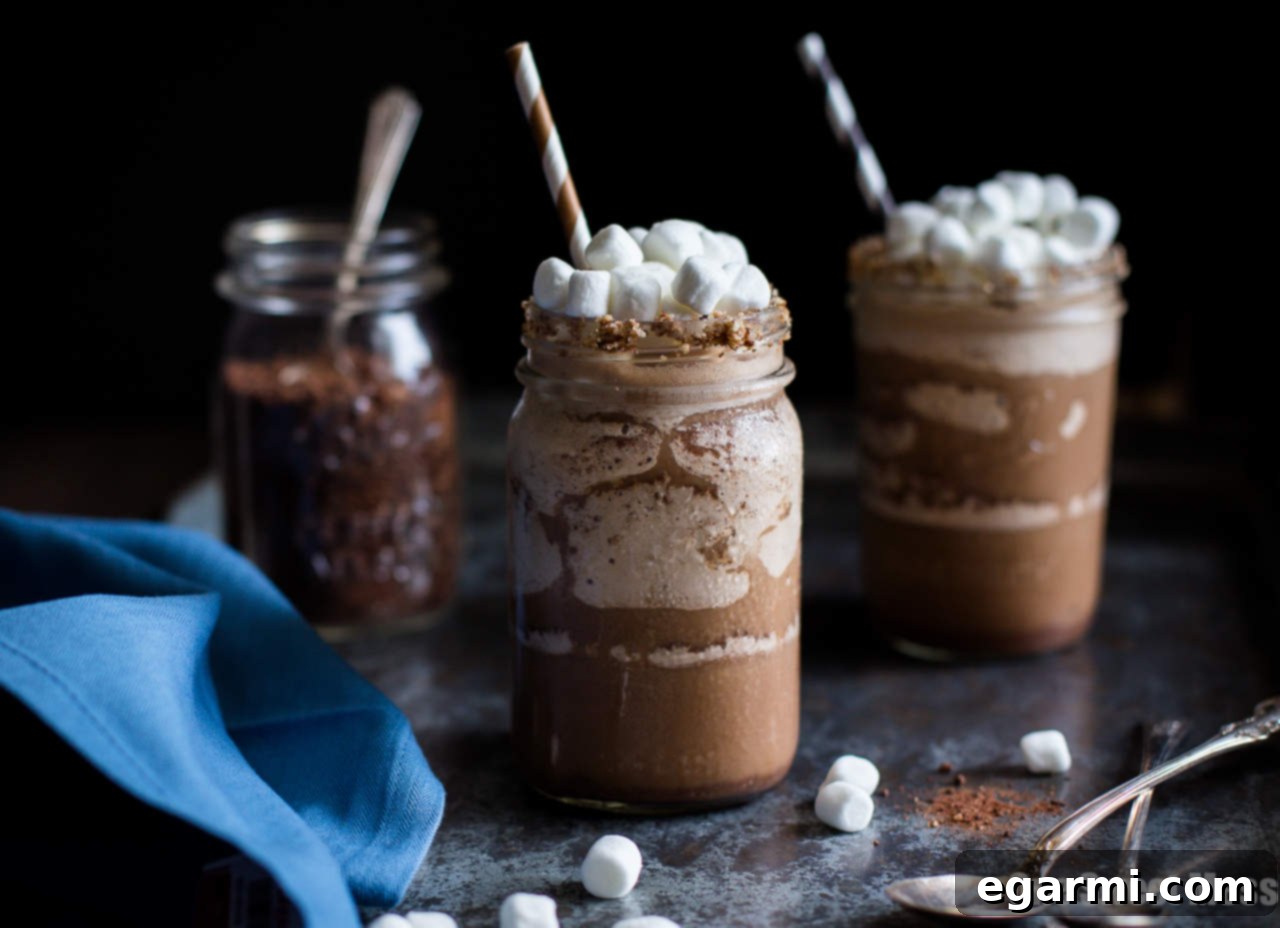 Spiked Frozen Smores Cocoa 4 Three mason jars filled with Boozy S'mores Frozen Hot Chocolate, garnished with mini marshmallows and ready to serve