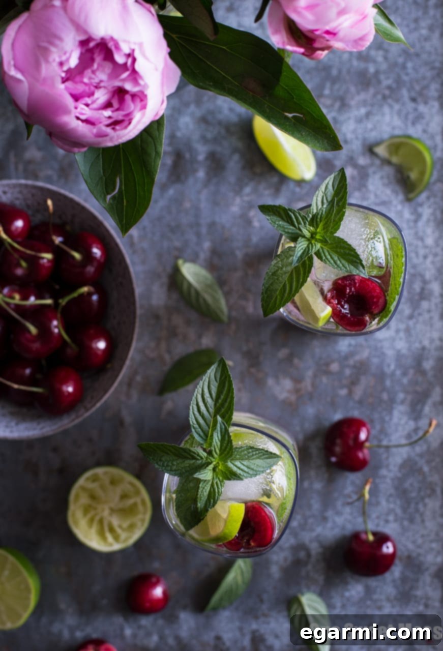 Pouring a Black Cherry Mojito into a glass with ice, showing the vibrant red color of the drink