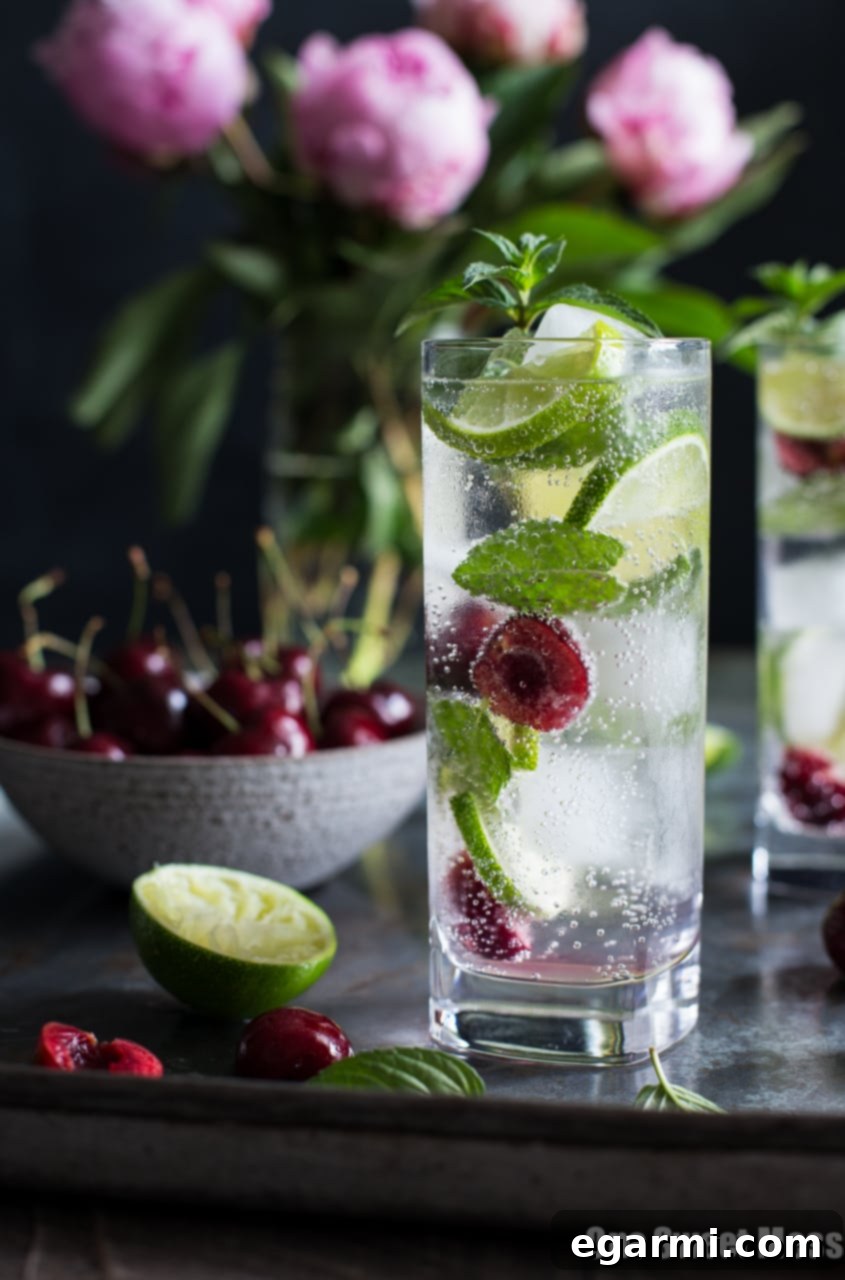 Close-up view of a garnished Black Cherry Mojito with a slice of lime, mint sprig, and a cherry on top