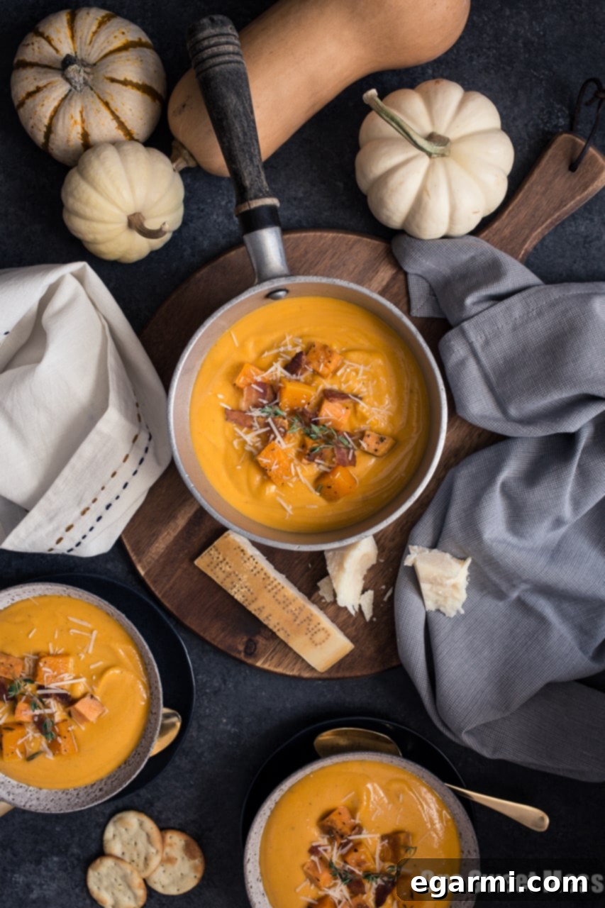Rich and velvety Roasted Butternut Squash & Sweet Potato Soup in a bowl, garnished with fresh herbs and a swirl of cream.