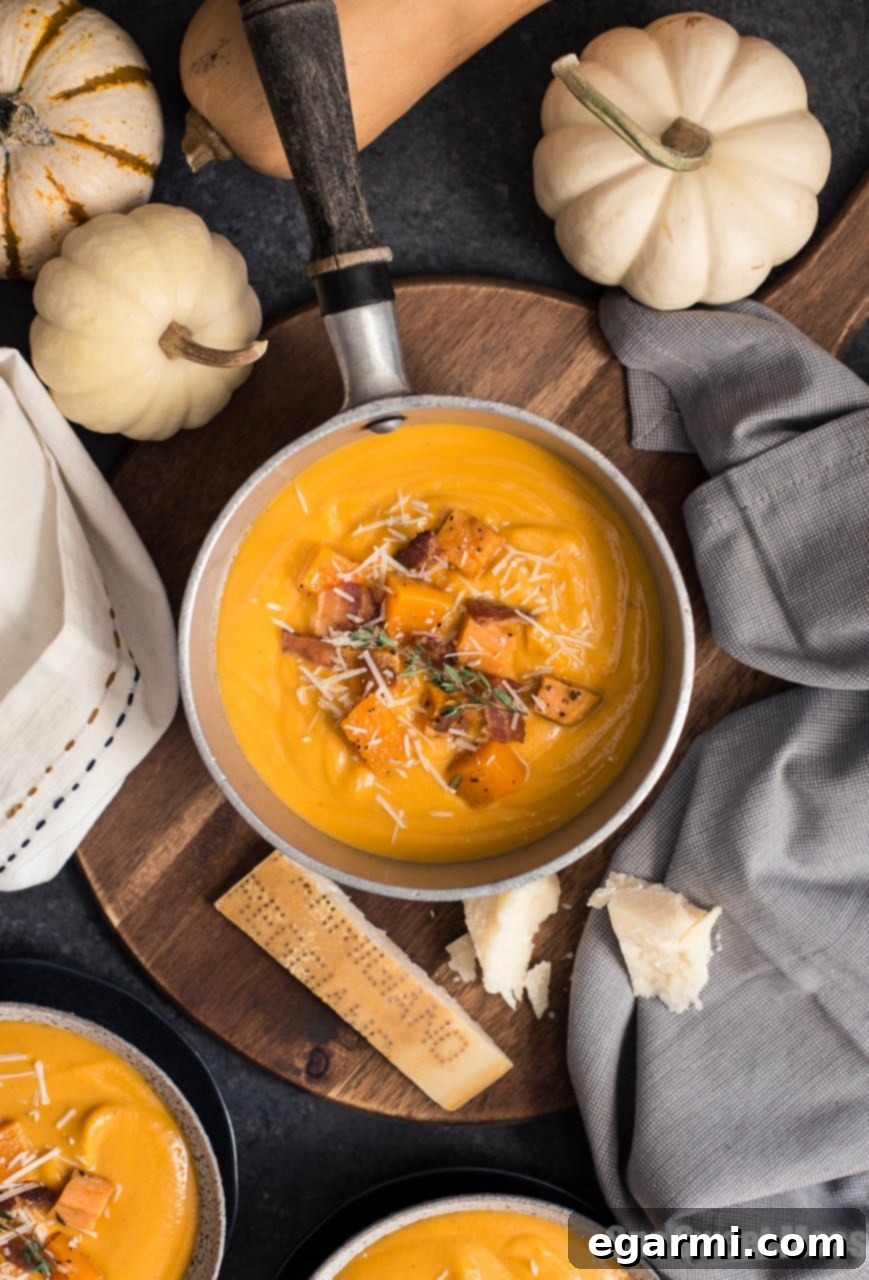 A beautifully presented bowl of creamy Roasted Butternut Squash & Sweet Potato Soup, garnished with fresh herbs and a drizzle of olive oil.
