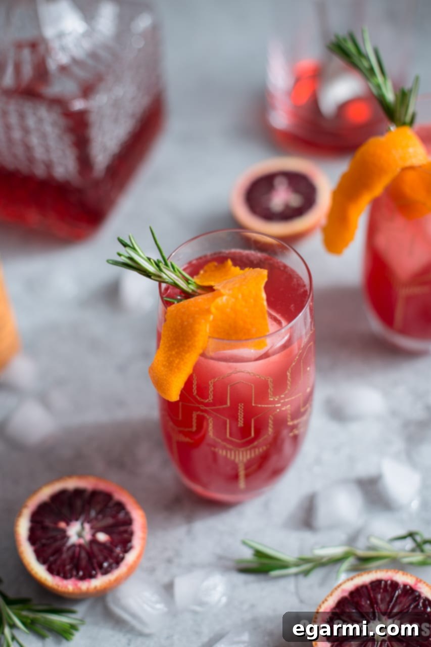 Three Blood Orange Campari Gin Fizz cocktails arranged on a wooden surface.