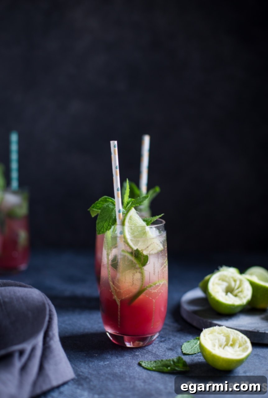 Pineapple Cranberry Mojito served in a tall glass, garnished with fresh pineapple and mint