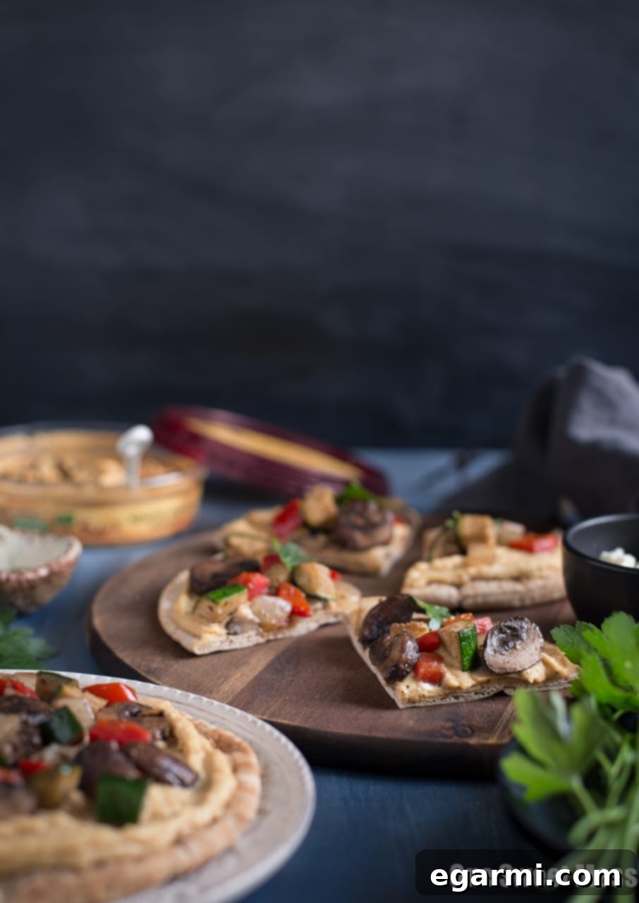 Layering creamy hummus on grilled pita bread for a delicious Mediterranean snack.
