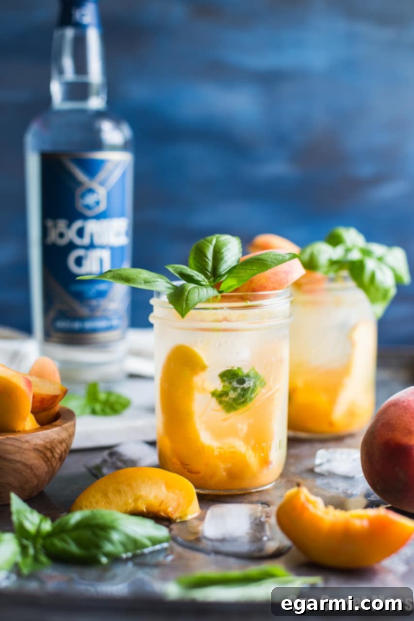 Finished Peach Basil Gin Fizz Cocktail with a peach slice and basil garnish