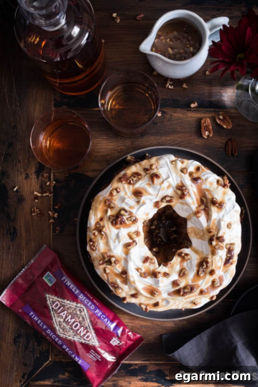 Sweet Potato Bundt Cake with Marshmallow Frosting being drizzled with Bourbon Pecan Caramel
