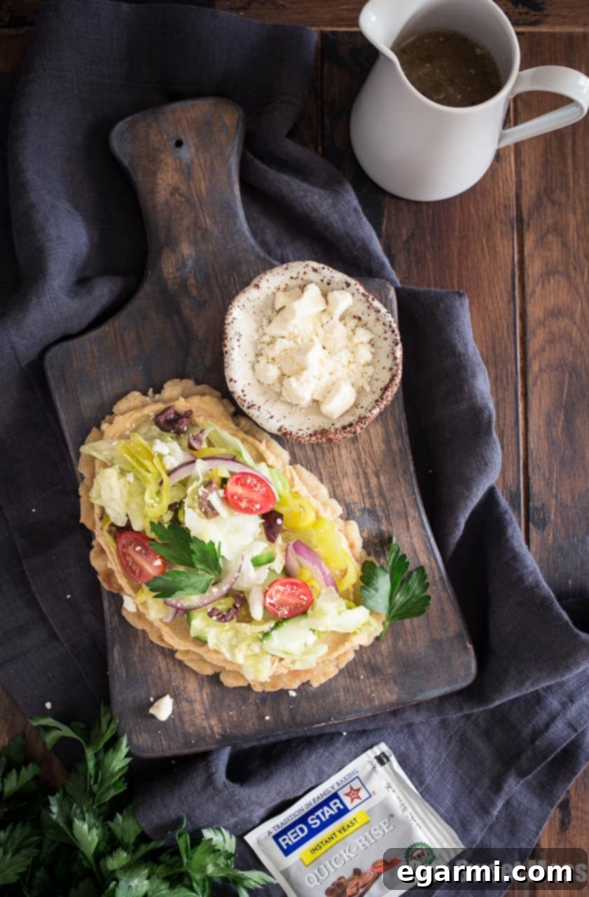 Delicious Gluten-Free Greek Salad Naan Pizza topped with fresh vegetables and creamy hummus.