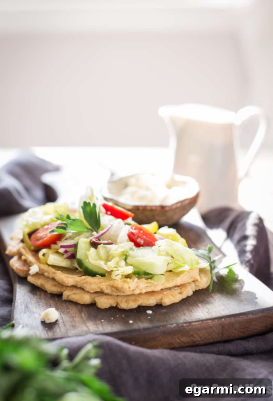 Close-up of a Gluten-Free Greek Salad Naan Pizza showing the texture of the naan and freshness of the salad.