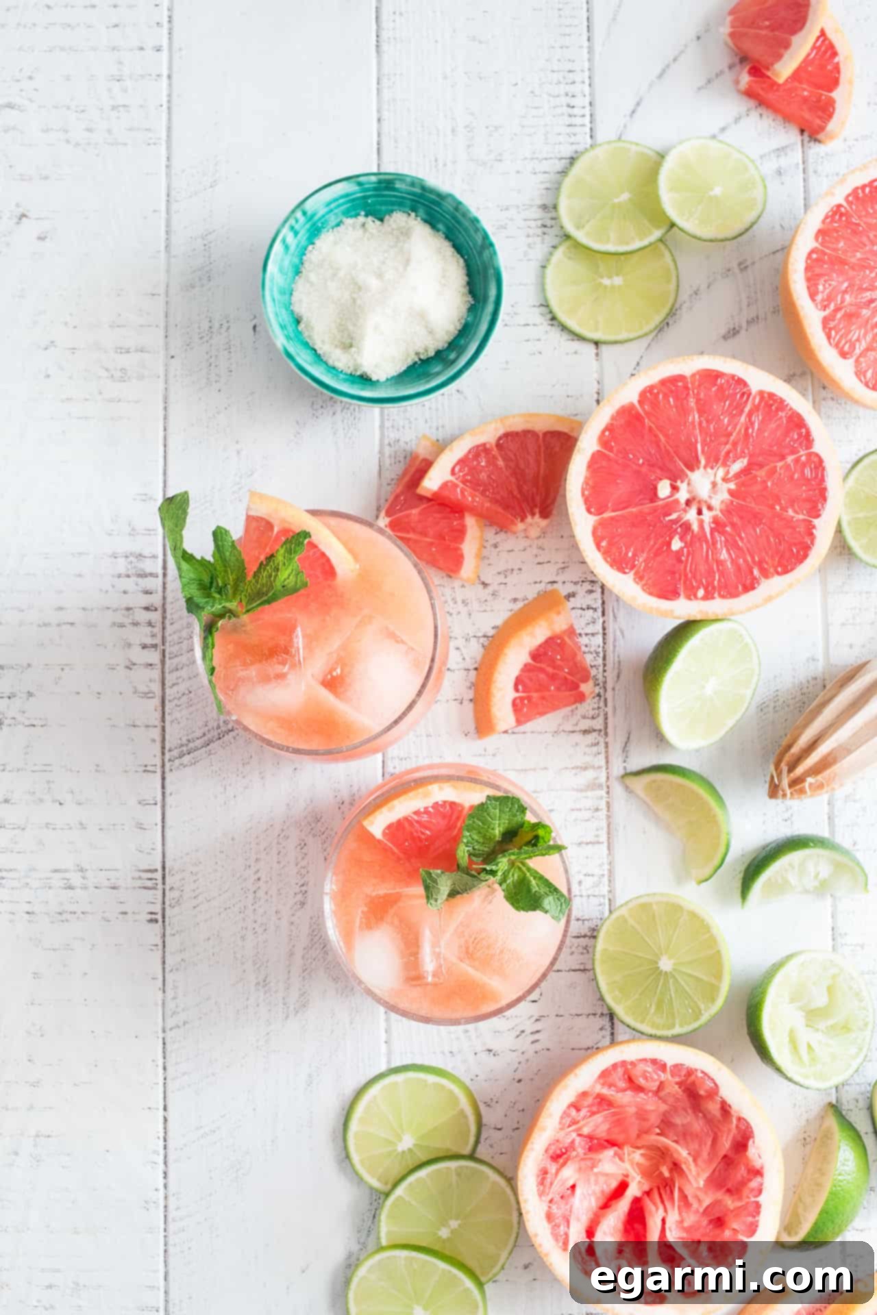 Refreshing Paloma Cocktail with grapefruit and lime slices, showcasing a vibrant pink hue in a tall glass.