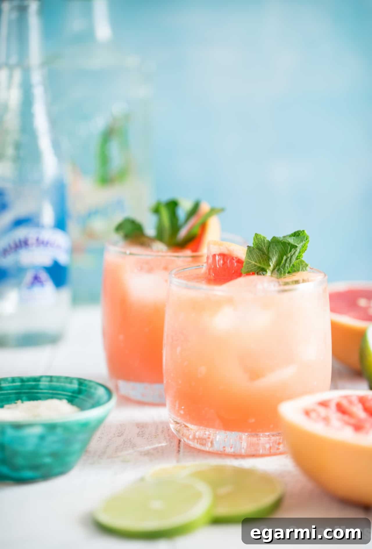 Close-up of a Paloma cocktail being prepared, with a bartender's hands adding ingredients to a shaker.