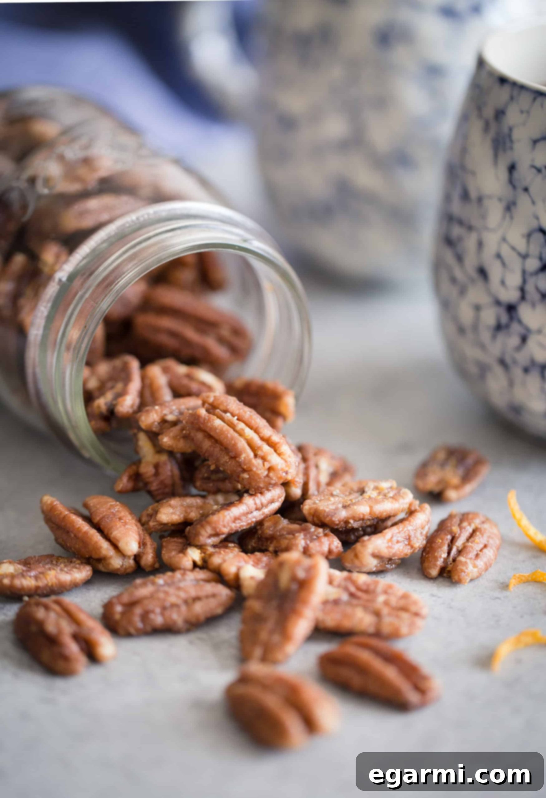 Individual ingredients for Maple-Orange Roasted Pecans laid out, including pecans, orange, maple syrup, coconut oil, and an egg.