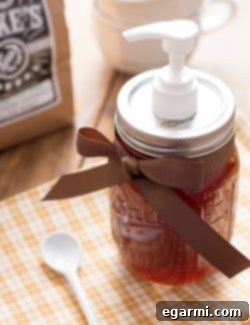 Homemade Pumpkin Spice Syrup in a glass bottle with spices around it.