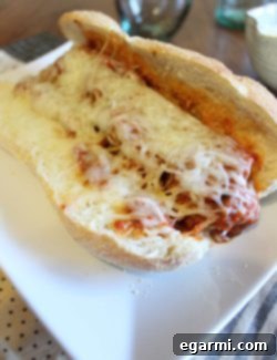 Saucy Meatball Heroes 2 A delicious homemade meatball sub overflowing with meatballs, marinara, and melted cheese, served on a plate.