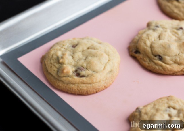 Chocolate chip cookie dough balls scooped onto a baking sheet, with sides pinched up.