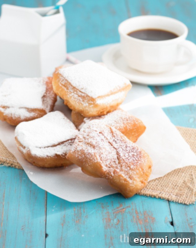 A mountain of powdered sugar being dusted over warm Buttermilk Beignets
