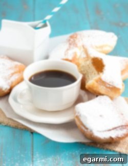 A plate of freshly fried Buttermilk Beignets, generously dusted with powdered sugar and ready to serve