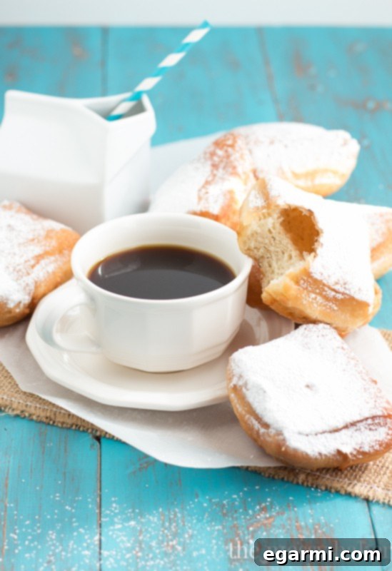 Close-up of golden Buttermilk Beignets piled high with powdered sugar