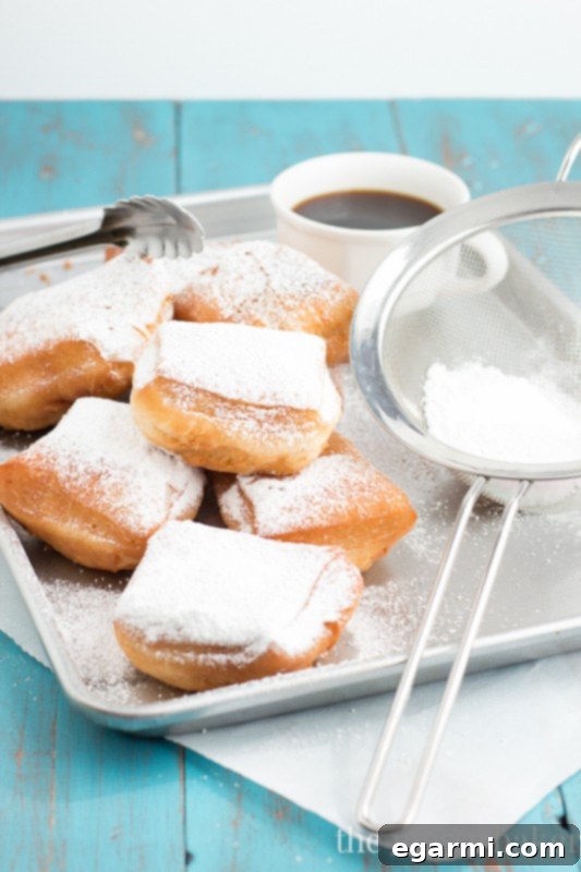 Individual golden Buttermilk Beignet, generously coated in powdered sugar
