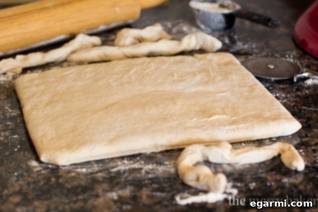 Using a pizza cutter to trim the edges of the beignet dough