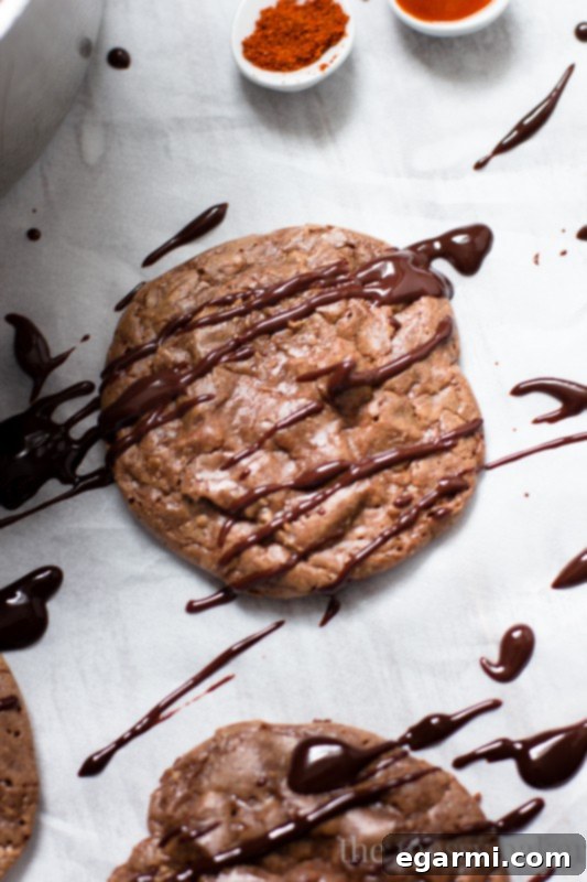 A spoonful of rich, glossy Sriracha Ganache being drizzled over a Double Chocolate Brownie Cookie.