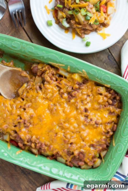 Hearty Loaded Potato and Baked Bean Bake 5 Close-up of ingredients being assembled for the Loaded Baked Potato & Baked Bean Casserole, showcasing potatoes, peppers, and onions