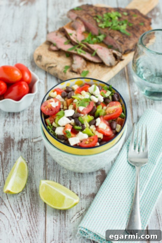 Juicy mesquite-grilled flank steak slices served alongside a vibrant corn and black bean salad, creating a perfect summer meal.