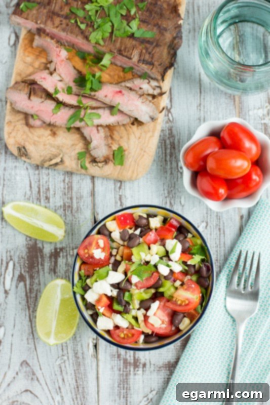 Raw flank steak marinating in a flavorful mesquite sauce, absorbing rich smoky notes before grilling.