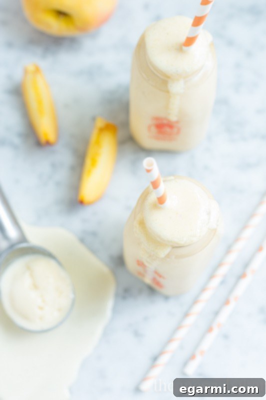 Close-up of a frothy Peach Pie Milkshake, showcasing its creamy texture and the golden hue of fresh peaches.