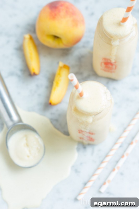 Two tall glasses of Peach Pie Milkshake on a rustic wooden surface, highlighting their tempting appeal.