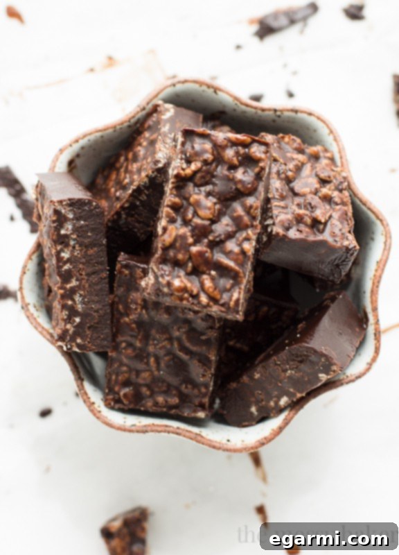 A top-down view of Carob Peanut Butter Freezer Fudge squares scattered with carob powder, showcasing their appealing texture and inviting presentation on a rustic background.