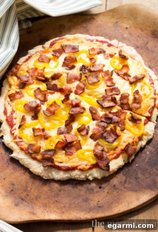 A slice of homemade gluten-free pizza, topped with melted mozzarella, bacon, and banana peppers