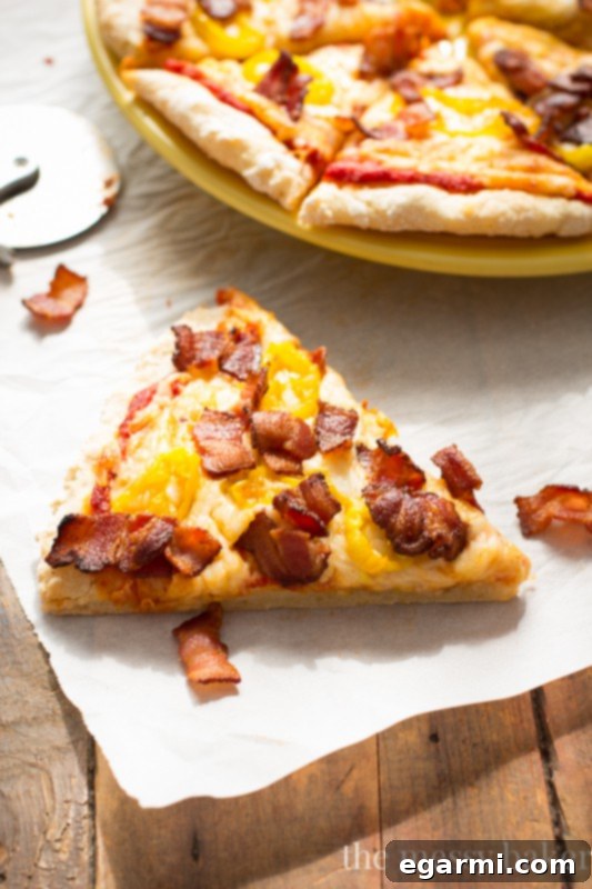 Close-up of a generously topped slice of Gluten-Free Bacon Banana Pepper Pizza