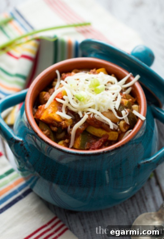 A delicious Harvest Chili Bowl topped with melted cheese, sour cream, and green onions, ready to enjoy.