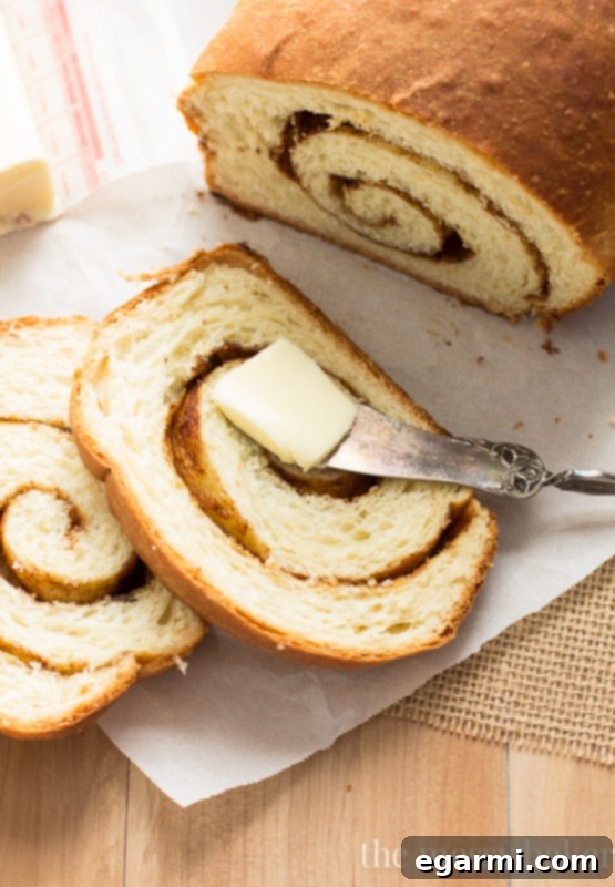 Detailed shot of a single homemade Cinnamon Swirl Loaf on a wooden cutting board, ready to be sliced, emphasizing the rustic charm and comforting appeal of the bread.