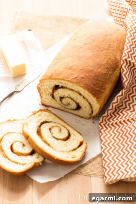 A beautifully sliced Cinnamon Swirl Loaf revealing the intricate, delicious layers of cinnamon, brown sugar, and pecans perfectly swirled within the soft, fluffy bread.