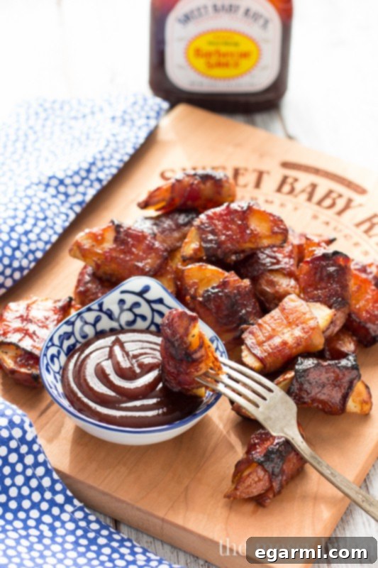 Close-up of golden-brown bacon-wrapped potato wedges, glistening with barbecue sauce glaze, ready to be served as an irresistible party appetizer.