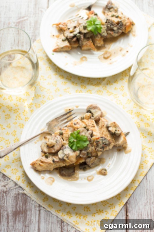 Close-up of perfectly cooked chicken breast in rich creamy sauce with mushrooms and capers