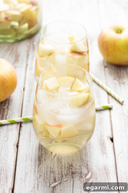 Garnishing Sparkling Caramel Apple Sangria with fresh apple slices