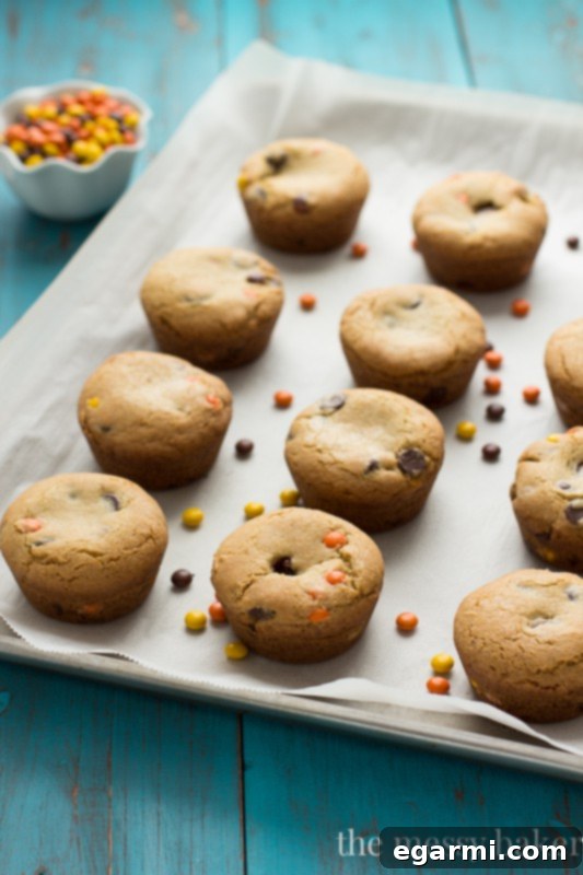 Freshly baked Peanut Butter Stuffed Chocolate Chip Cookie Cups cooling in a muffin tin